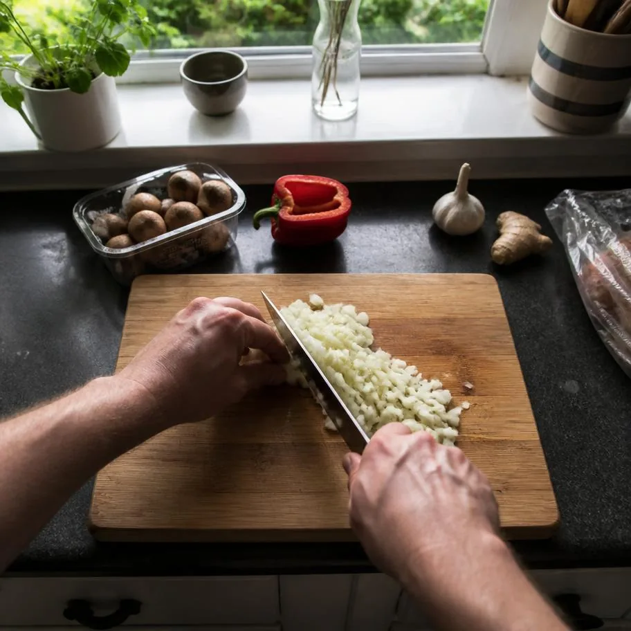 Mãos cortando legumes na cozinha